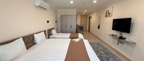 A hotel room with two beds, a TV, a desk, and a wardrobe.