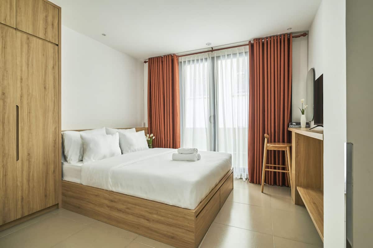 Une chambre d’hôtel moderne avec un lit en bois, un bureau avec une chaise et une grande armoire.