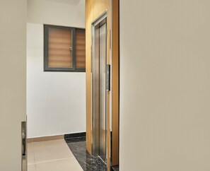 A hallway with a wooden door and a metal elevator. - Mihn Suites Ben Thanh (Ho Chi Minh City)