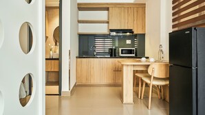 A modern kitchen with wooden cabinets, a black refrigerator, a microwave, and a dining area with two chairs. - Mihn Suites Ben Thanh (Ho Chi Minh City)