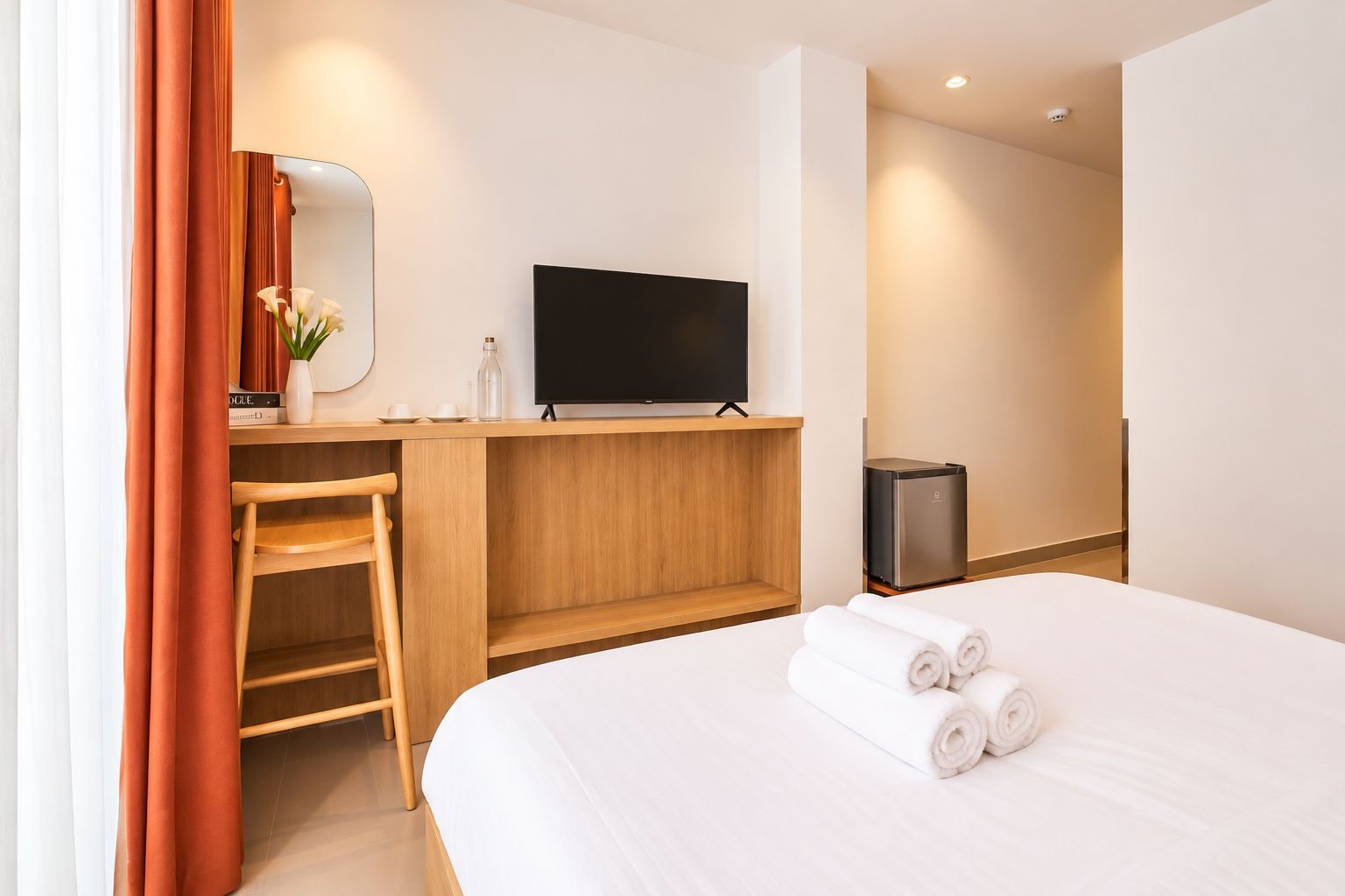 A hotel room with a bed, a desk, a television, and a trash bin.