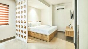 Un dormitorio moderno con estructura de cama de madera, ropa de cama blanca y una pequeña mesita de noche de madera.