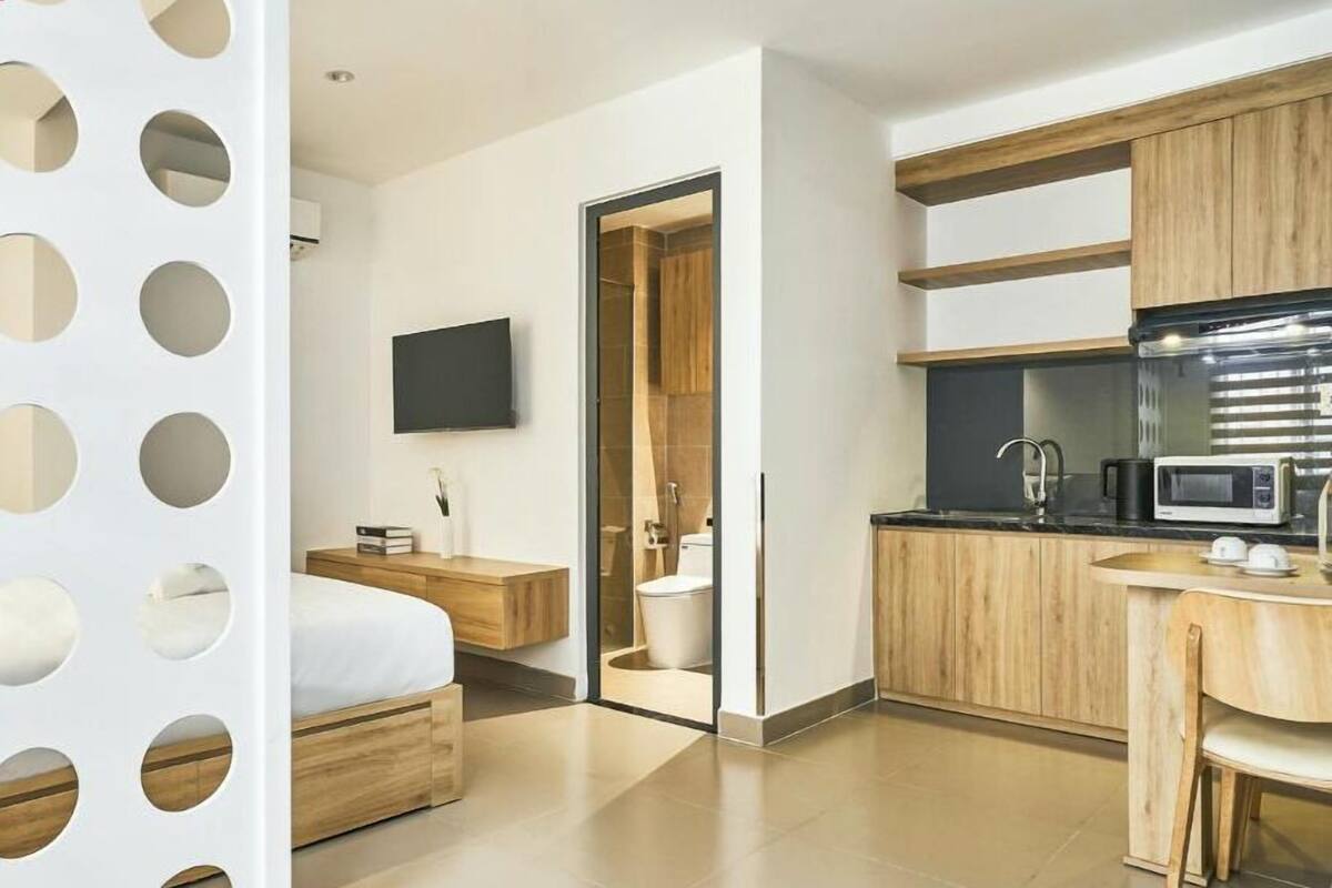 Une chambre d’hôtel moderne équipée d’un lit, d’une table de chevet, d’une télévision et donnant sur la salle de bain.
