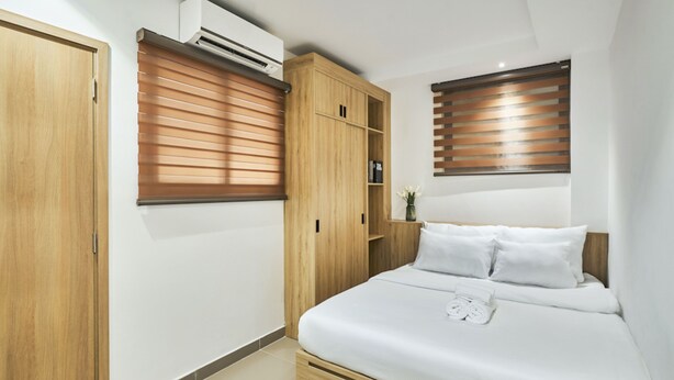 Un dormitorio con cama, armario de madera y estanterías empotradas.