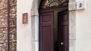 Un edificio de piedra con una puerta marrón oscuro y un letrero metálico encima.