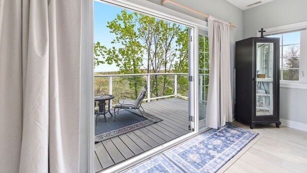 A room with a sliding glass door leading to a balcony, a small table with chairs, and a cabinet. - Lakefront Condo, Only Steps To The Beach (Michigan City)