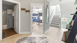 A hallway with a staircase, a door leading to a bathroom, and a view into a bedroom. - Lakefront Condo, Only Steps To The Beach (Michigan City)