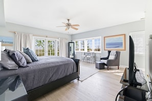 A bedroom with a bed, a desk, a chair, a television, and large windows. - Lakefront Condo, Only Steps To The Beach (Michigan City)