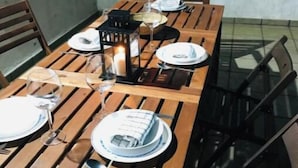 Una mesa de madera para comer con sillas, platos, vasos y una vela.