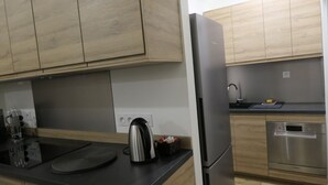 A modern kitchen with wooden cabinets, a stainless steel refrigerator, a built-in oven, and a sink.