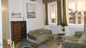 A living room with two green sofas, a wooden cabinet, and a small table.