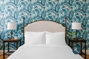 Classic bedroom with a large bed, bedside tables, and a small table with a vase of flowers.