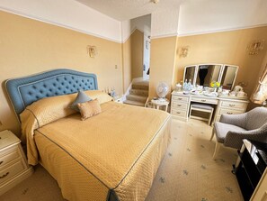 A hotel room with a large bed, a desk, a chair, a dresser, and a mirror. - Hotel Riviera Sidmouth (Sidmouth)