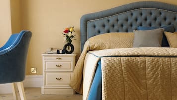 A bedroom with a tufted headboard, a bedside table with a vase of flowers, and a chair.