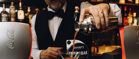 Ein Barkeeper gießt ein Getränk in ein Glas hinter der Bar ein.