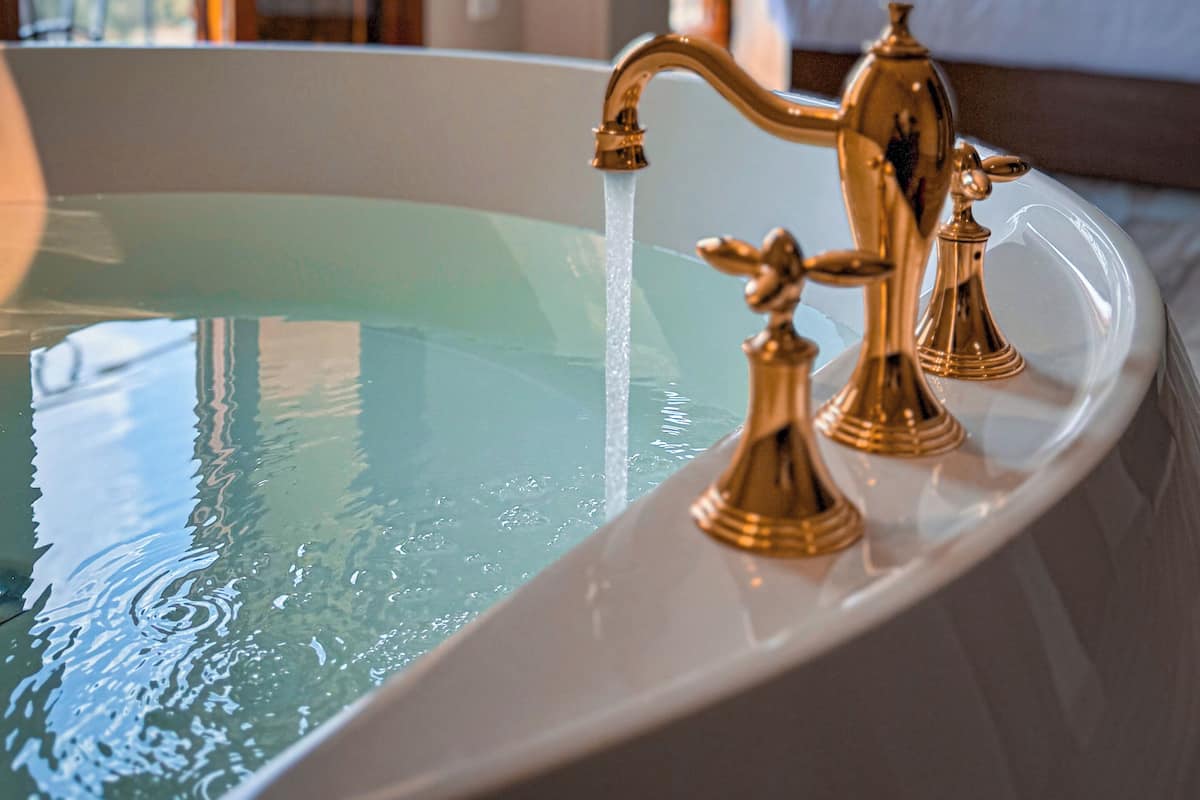A bathtub with gold fixtures in a hotel room.