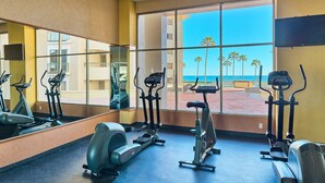 A gym with exercise equipment and large windows overlooking a beach. - Penthouse Beachfront at Sonoran Spa (Puerto Peñasco)