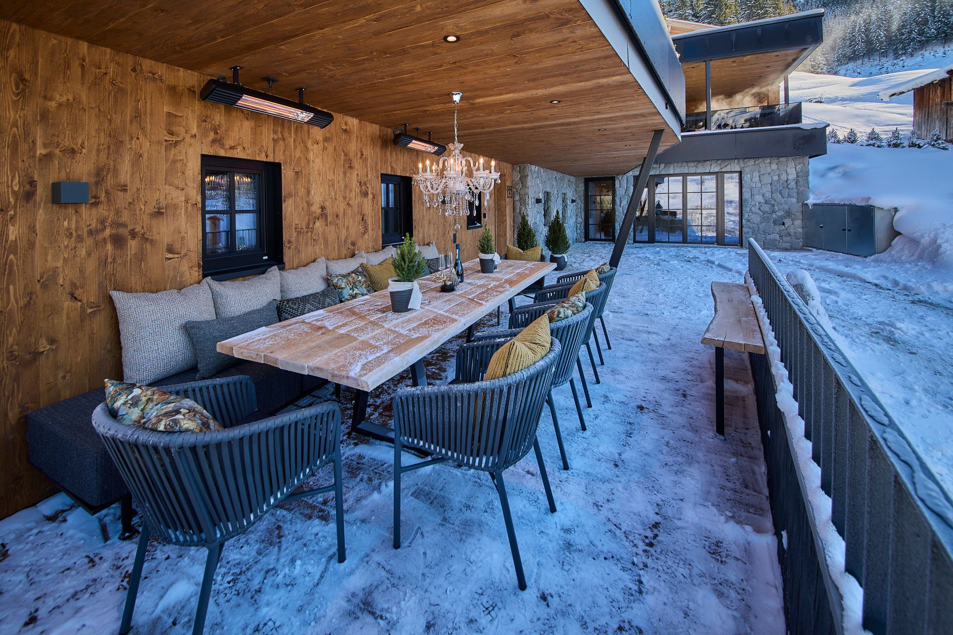 A cozy wooden interior with a dining area, seating, and a stone wall.