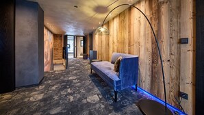 Un pasillo moderno con pared de madera, sofá azul y alfombra estampada.