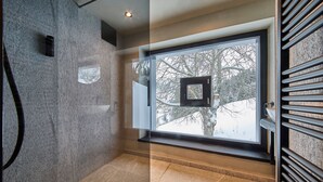 Un baño moderno con un ventanal grande, suelo de baldosas y un perchero para toallas.