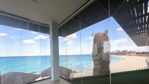 A balcony with a clear view of a beach and ocean.