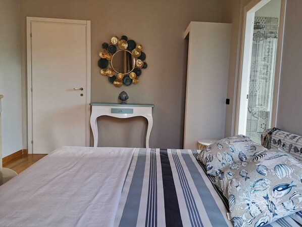 Un dormitorio con cama, cómoda, mesita de noche y un espejo decorativo.