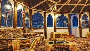 A traditional room with patterned furniture, a decorative vase, and large windows with views of the outside. - White Sands Resort- Best Resort in NUBRA (Leh)