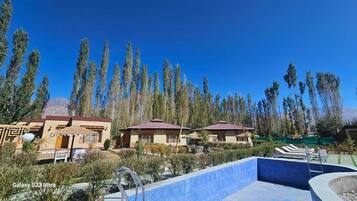 Una piscina al aire libre de temporada, sombrillas, tumbonas