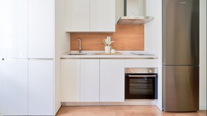 Une cuisine moderne avec des meubles blancs, un réfrigérateur Bosch en acier inoxydable et un four encastré.