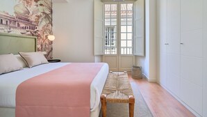 Une chambre à coucher comprenant un lit, un banc, une peinture murale, une fenêtre et une porte.