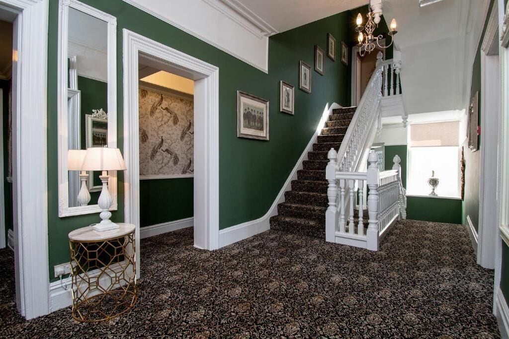 A staircase with white balustrades and a patterned carpet.
