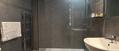 A modern bathroom with a glass-enclosed shower, a white sink, and a toilet.