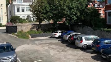 A parking lot with several cars, a stone wall, and a large tree.