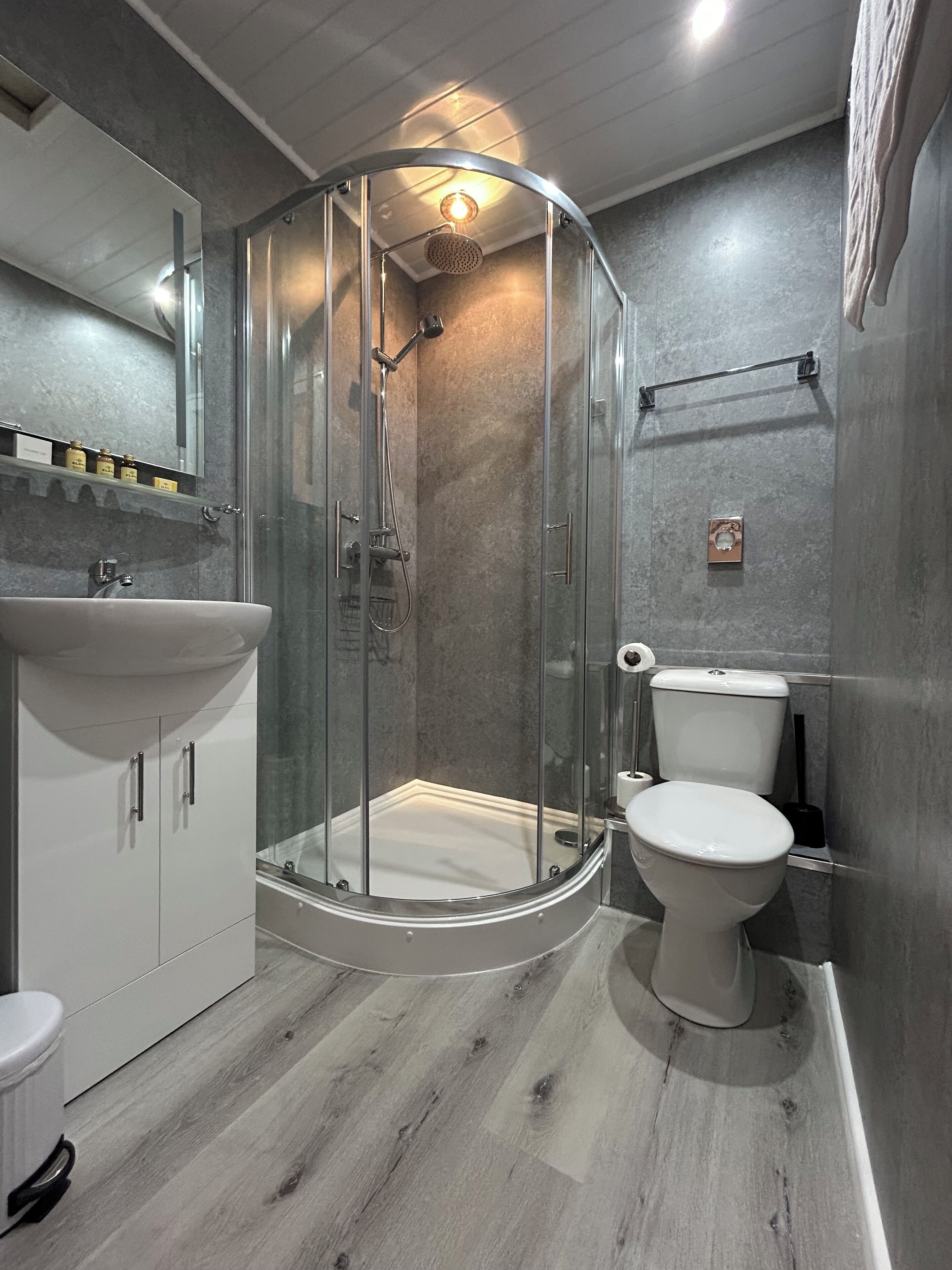 A modern bathroom with a glass-enclosed shower, a white sink, and a toilet.