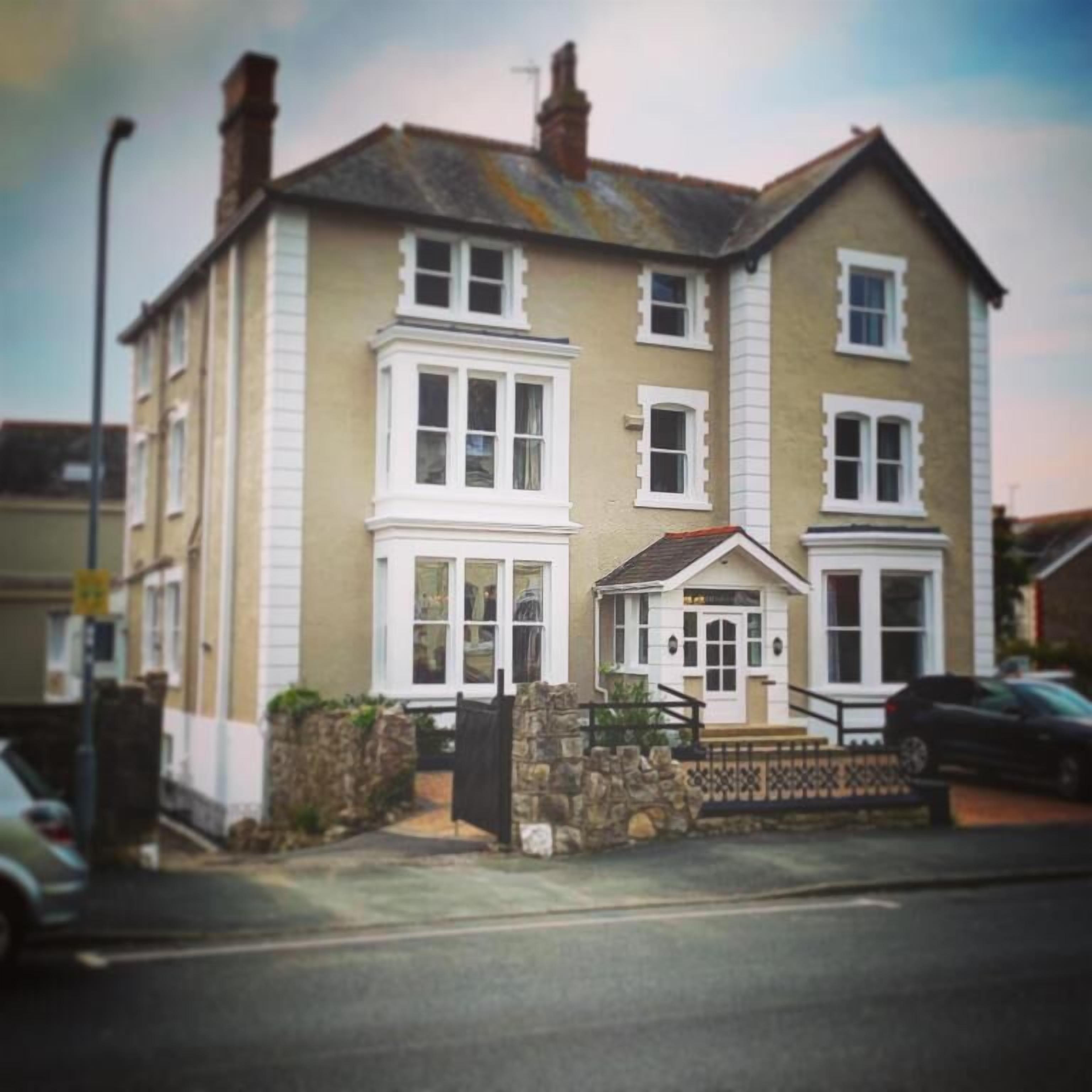 A two-story house with a bay window on the first floor and a small porch with a door.
