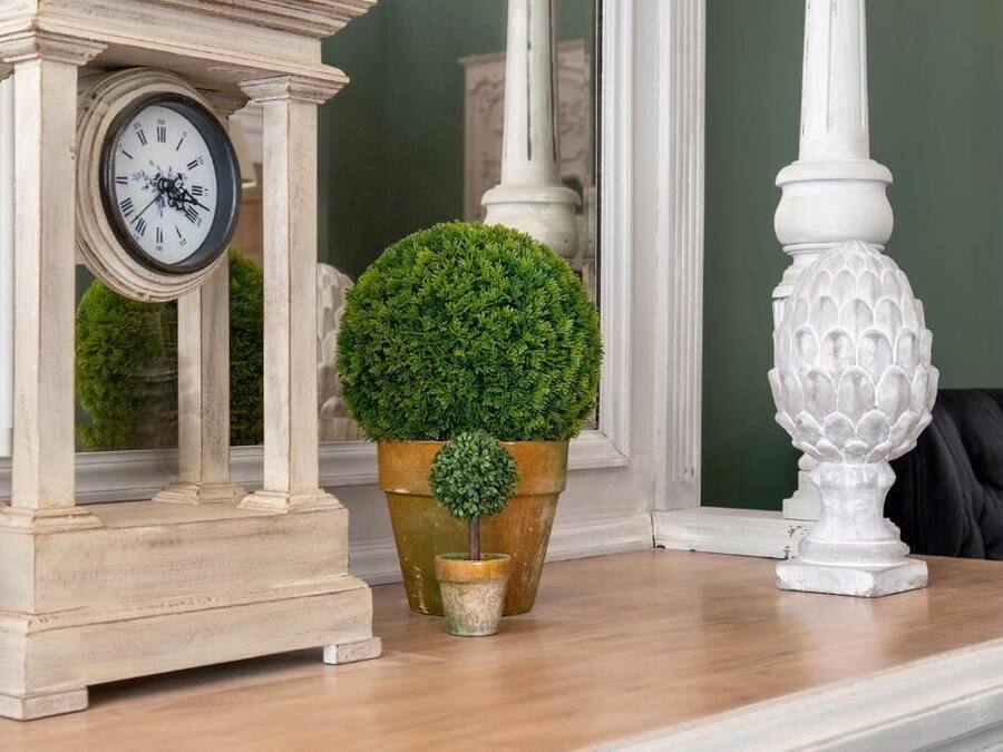 A clock, a potted plant, and a decorative vase on a wooden surface.