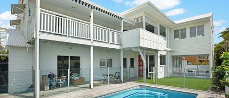 A two-story house with a swimming pool, a balcony, and a patio area.