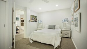 Un dormitorio con una cama grande, mesitas de noche con lámparas y cuadros en la pared.
