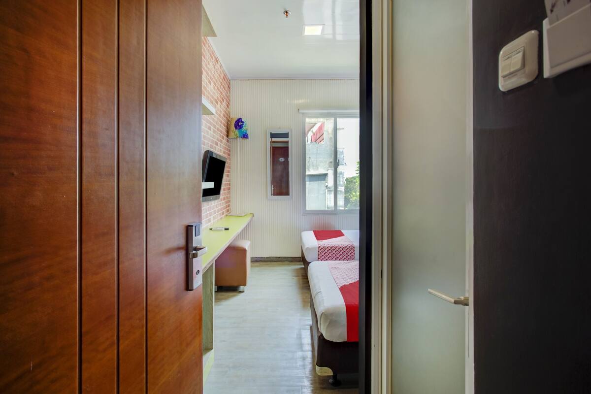 A corridor leading to a room with a bed, a desk, and a television.