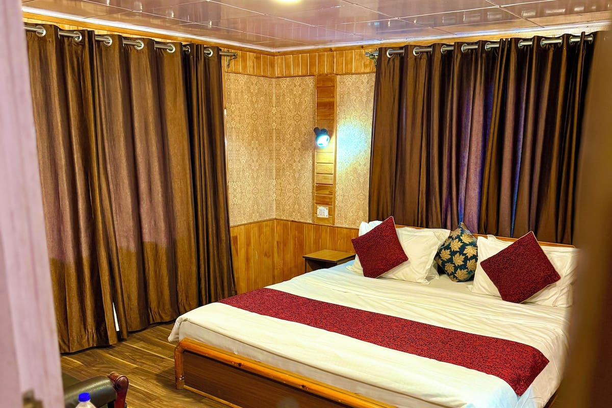 A hotel room with a wooden bed, a nightstand, and a bathroom visible through a curtain.