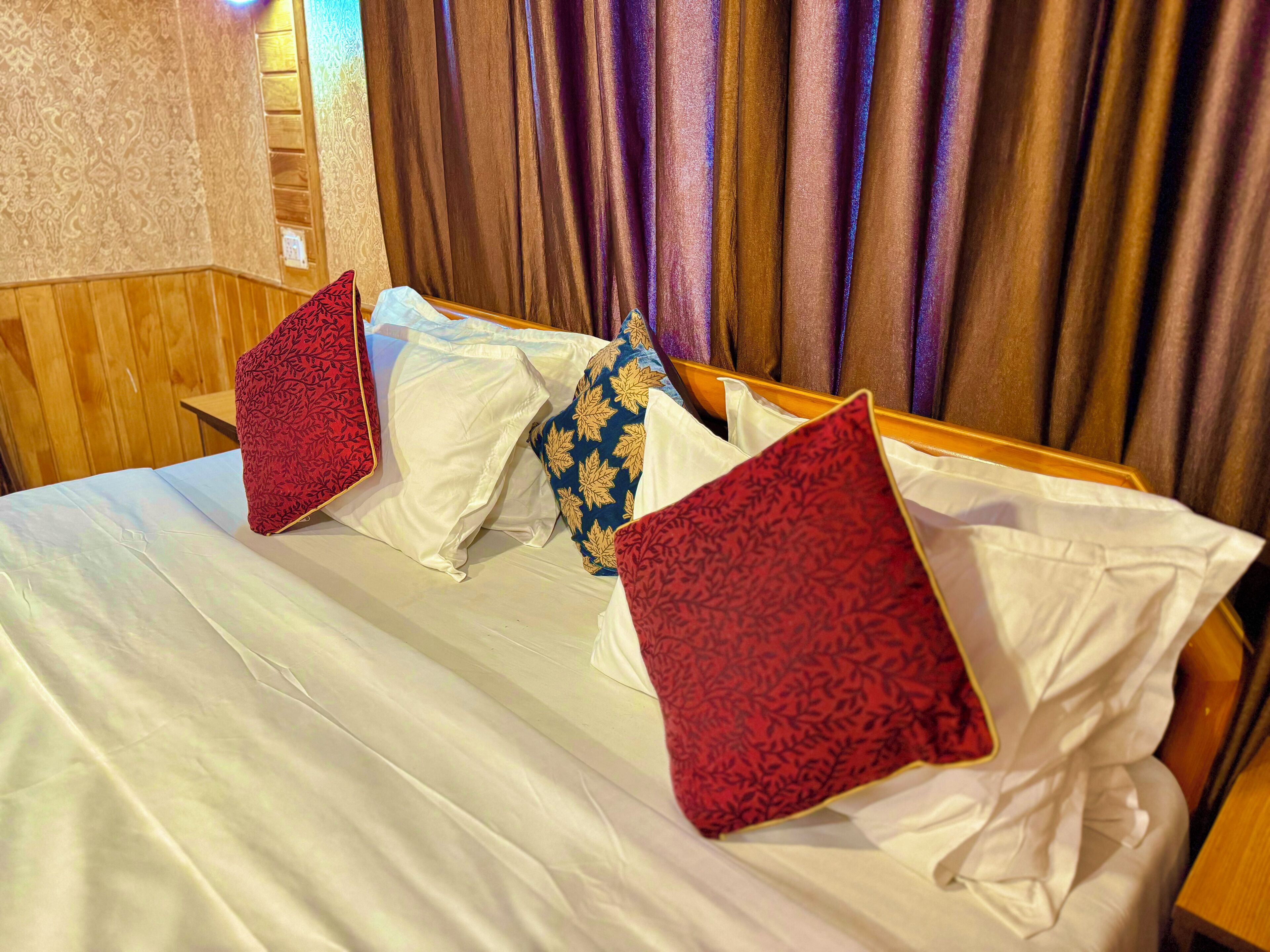 Quarto de hotel com cama bem arrumada, cabeceira de madeira e vista para cortinas.