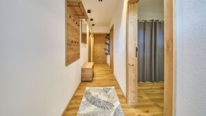 Un pasillo estrecho con suelo de madera, un tapete estampado y un perchero de madera.