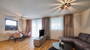 Una sala de estar moderna con un sofá, una mesa de centro, un televisor y un comedor con sillas y una mesa.