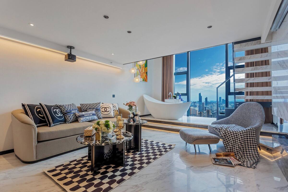 Una sala de estar moderna con sofá, mesa de centro y sillón, una ventana grande con vistas a la ciudad y una bañera.