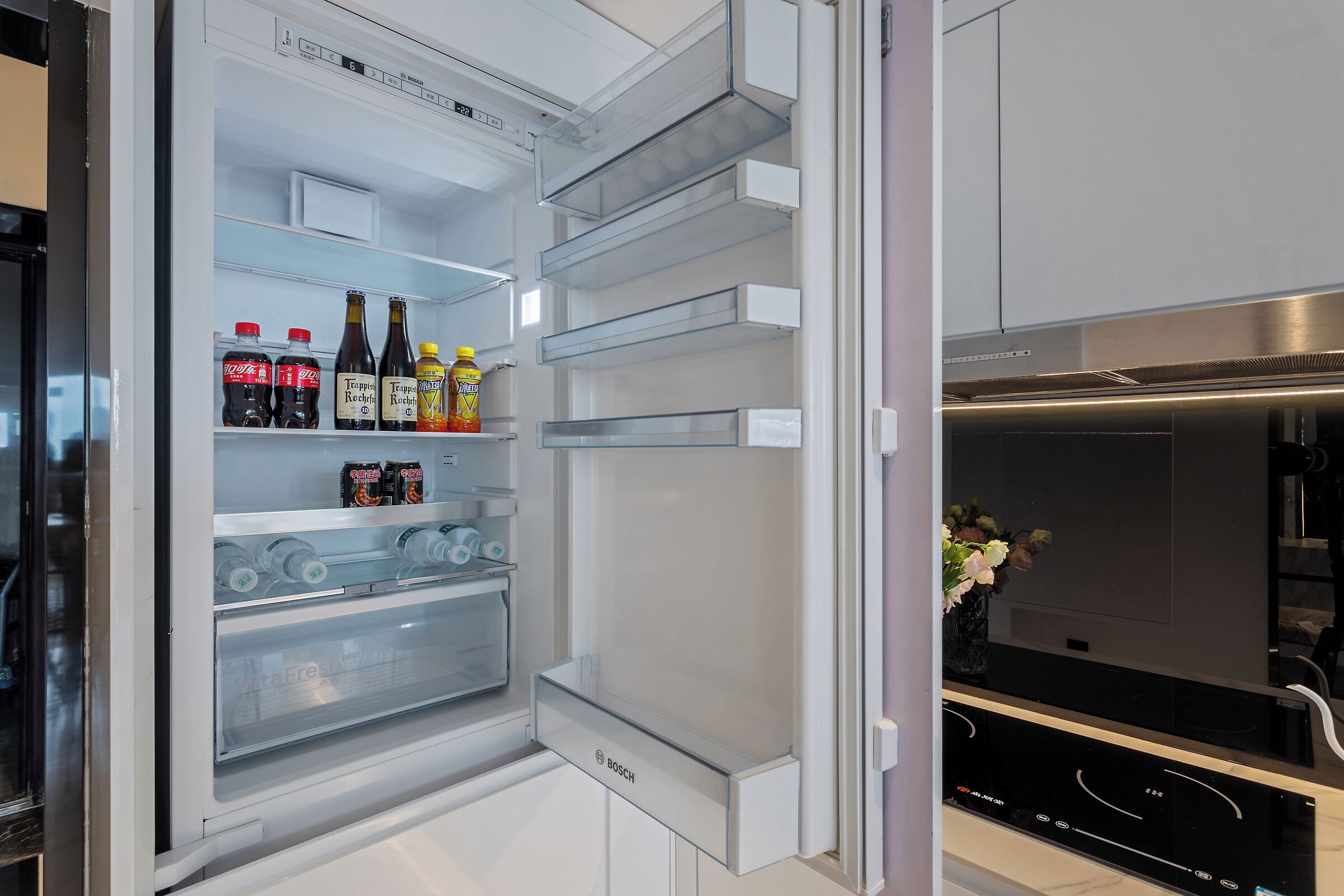 Een moderne keuken met een inbouw Bosch koelkast, een roestvrijstalen afzuigkap en een marmeren aanrecht.