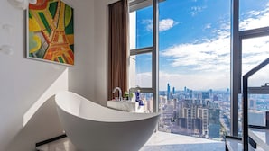 A modern bathroom with a freestanding bathtub, a city view, and a large window. - Hotel high sky view hotel (Kunming)