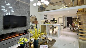 A modern living room with a flat-screen TV, a fireplace, and a dining area with a bar. - Hotel high sky view hotel (Kunming)