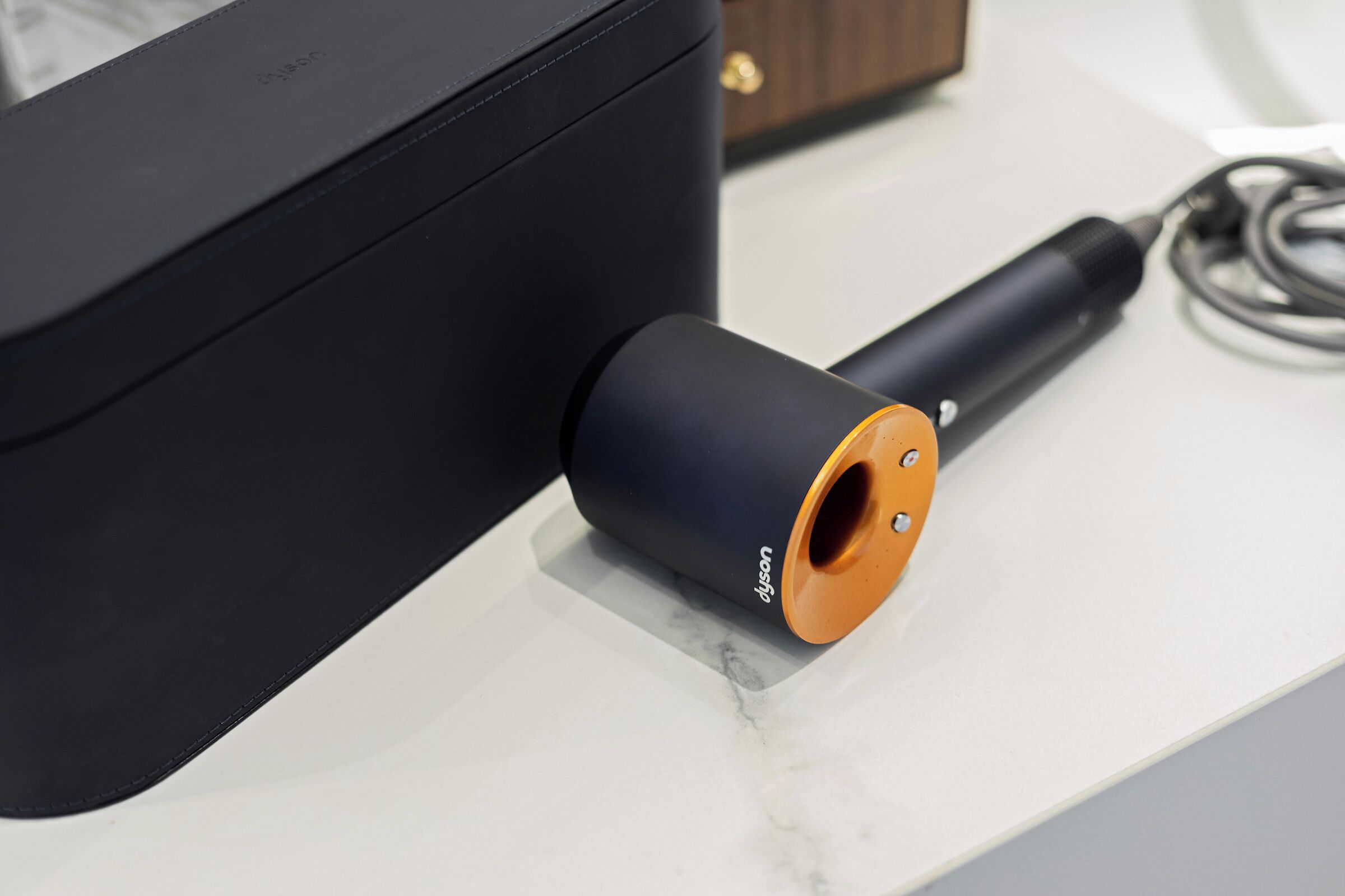 A black cylindrical object with an orange top on a white surface.
