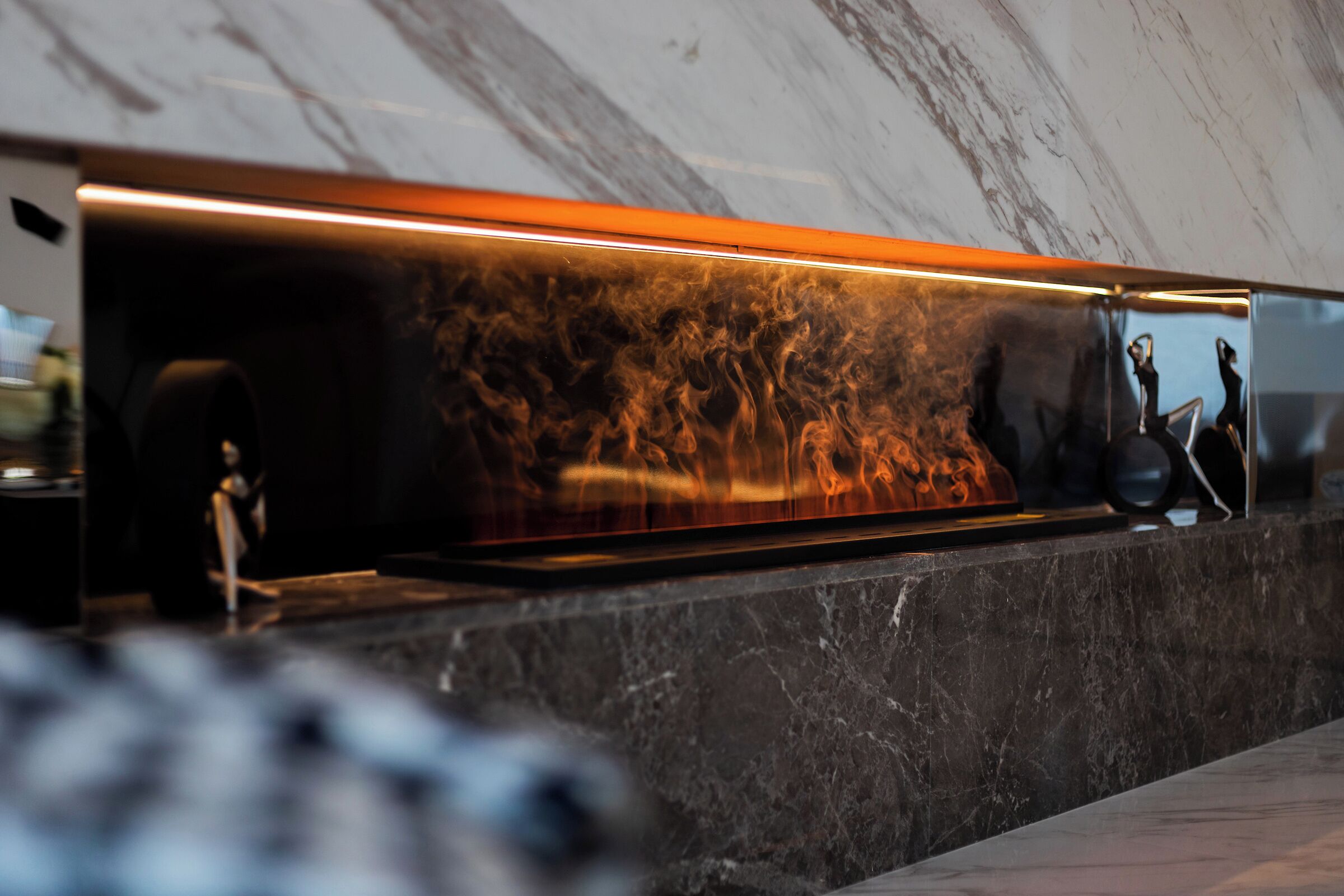 A modern reception area with a marble wall and a sleek, illuminated counter.