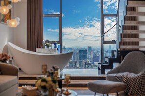 A modern living room with a large window offering a city view, a white curved sofa, and a houndstooth patterned armchair. - Hotel high sky view hotel  (Kunming)